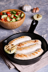 Sausages in rustic pan with onion. Frying pan with fried sausage and vegetables