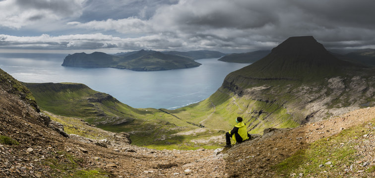 Stremnoy island, Faroe Islands, Denmark. Man watching the Vagarfjordur from the top of the mountain. (MR)