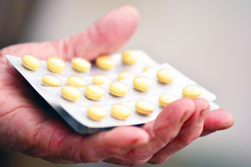 Old woman holding pills in her hand. Elderly female hand with pills or pharmaceutical meds.