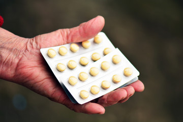 Old woman holding pills in her hand. Elderly female hand with pills or pharmaceutical meds.