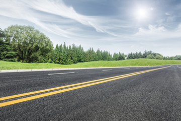 Asphalt road and green trees in the blue sky