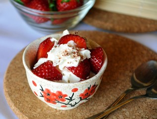 Refreshing snack chopped strawberries and whipped cream on a nice bowl.
