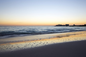 Sunrise on the beach. The caribbean sea is about to wake up. Sun coming up behind the horizon. Long exposure image.