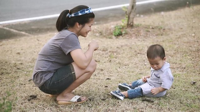 Asian mother let her 1 year and a month son to eat tamarind from tree in the park