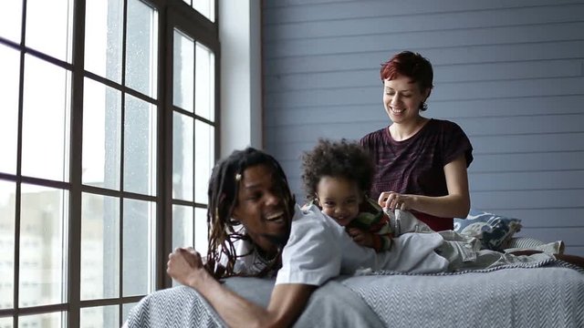 Happy mixed family playing with son in the bedroom