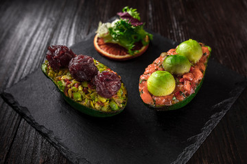 Salmon tartare and avocado salad on a black background