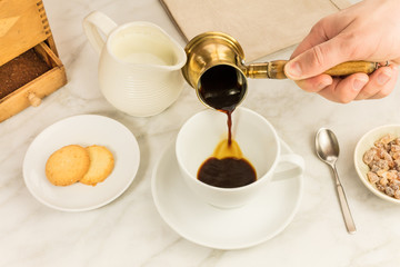 Coffee poured into cup, with milk jar and cane sugar