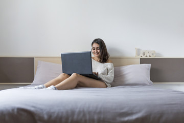 Obraz premium beautiful young woman lying on bed, using laptop. Lifestyle.