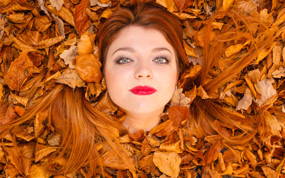 Pretty woman is lying between leaves.