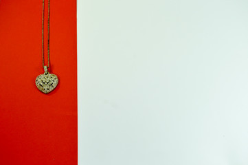 Fototapeta na wymiar Heart-shaped pendant on a red strip on a white background