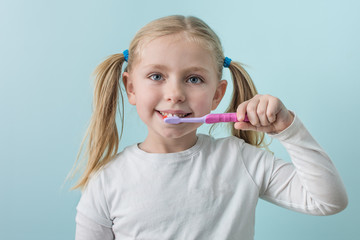 Adorable school age girl practicing good oral hygiene brushing teeth