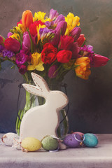 Spring fresh flowers with easter eggs and white pocelane rabbit, retro toned