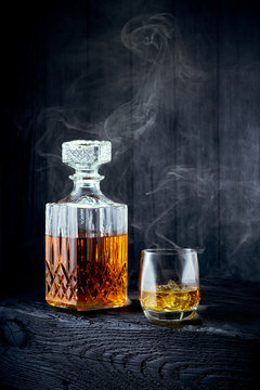 Glass of whiskey and carafe on a black wooden table