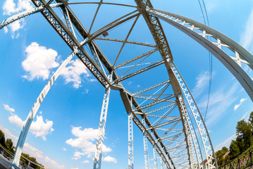 Obraz premium First in Russia steel arch bridge on river Msta. Historic iron bridge against blue sky