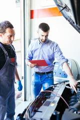 Two auto mechanics repairing car. Selective focus.