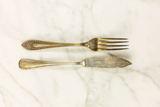 Vintage fork and fish knife on white marble with copyspace