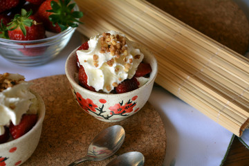 Refreshing snack chopped strawberries and whipped cream on a nice bowl.