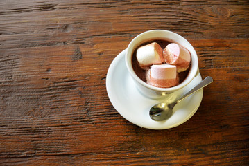 hot chocolate with marshmallows in a white cup on dark old wooden surface