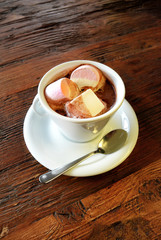 hot chocolate with marshmallows in a white cup on dark old wooden surface