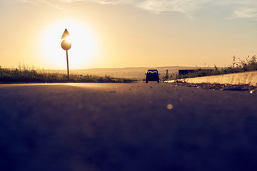 Zachodzące słońce za znakiem drogowym przy drodze 