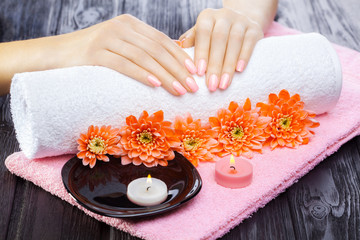 Obraz na płótnie Canvas beautiful pink manicure with chrysanthemum and towel on the black wooden table. spa