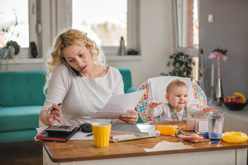 Mother talking on smart phone at home office