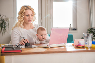 Mother working at home office with her baby