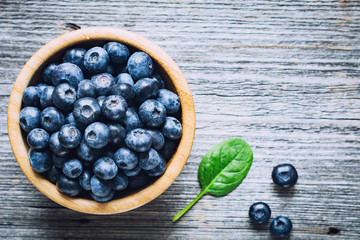 Bowl of fresh blueberries on rustic wooden background with copy space for text