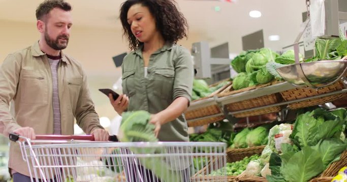Couple buying in grocery store using smartphone