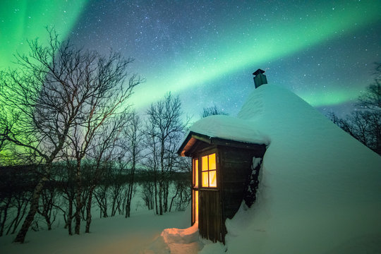 Northern lights over snowcapped cabin