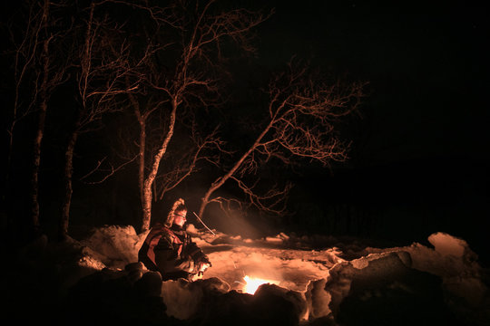 Man keeping warm in front of camp fire