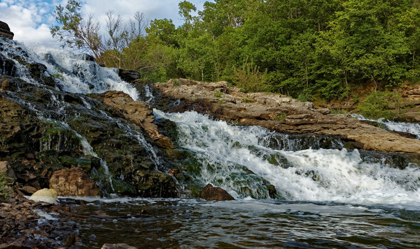 The water rushes over the Lake MacBride Waterfall. This waterfall has several main falls and numerous smaller falls.