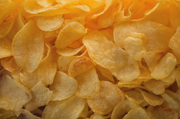 A lot of potatoes chips. Yellow salted potato chips as background. Chips texture.