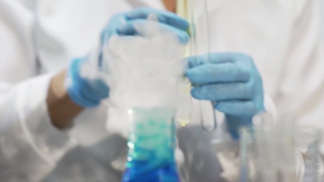 Chemist adding yellow substance into test tubes, conducting chemical research