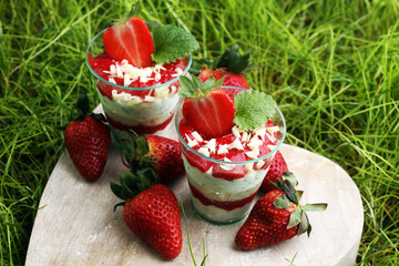 A cup of strawberries and cake with whipped cream