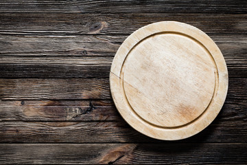Old cutting board on textured wooden table. Top view with copy space for text