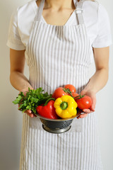 Cook holding a colander with vegetables, without face