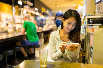 Woman using cellphone in japanese restaurant