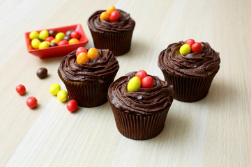 Easter cupcakes decorated with nest chocolate cream and sugar eggs on a wooden  background