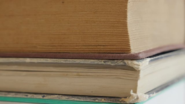 Vintage deckle edge paper material or stacked archives close-up 4K 2160p 30fps UltraHD tilting footage - Pile of old books darkened with shelf dust slow tilt 3840X2160 UHD video 
