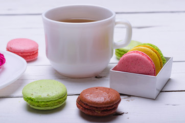 Almond cookies and a cup of tea on a wooden white table.