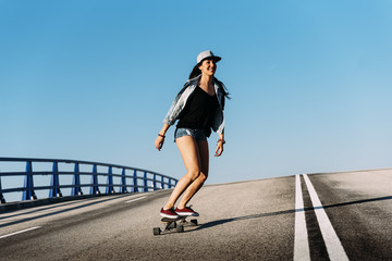 Beautiful skater woman riding on her longboard. © santypan