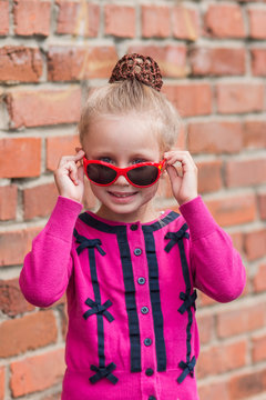 Cute little girl in sunglasses flirting, smiling, posing.