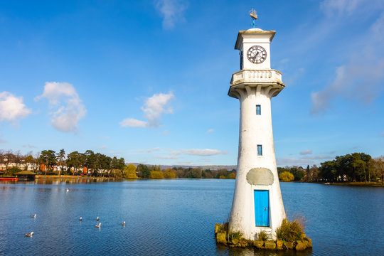Public Roath Park with Lake, Boat House, Boats and Robert Scott Memorial Lighthouse in Cardiff, Wales, UK. Photo taken in March 2017.