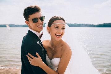 stylish wedding couple having fun near the lake with a blue sky in the background