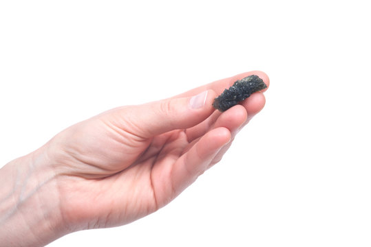 Young woman holding moldavite - form of tektite found along the banks of the river Moldau in Czech republic, isolated on white background