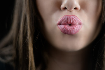 Juicy big lips of a young woman send a kiss, focus on lips,isolated black background