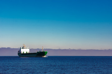 Green cargo ship moving in still water of Baltic sea