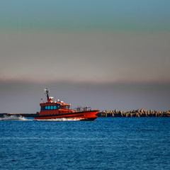 Red pilot ship moving past the breakwater dam in Riga, Europe