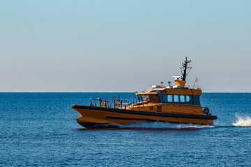 Fototapeta premium Yellow pilot ship moving at speed from the Baltic sea